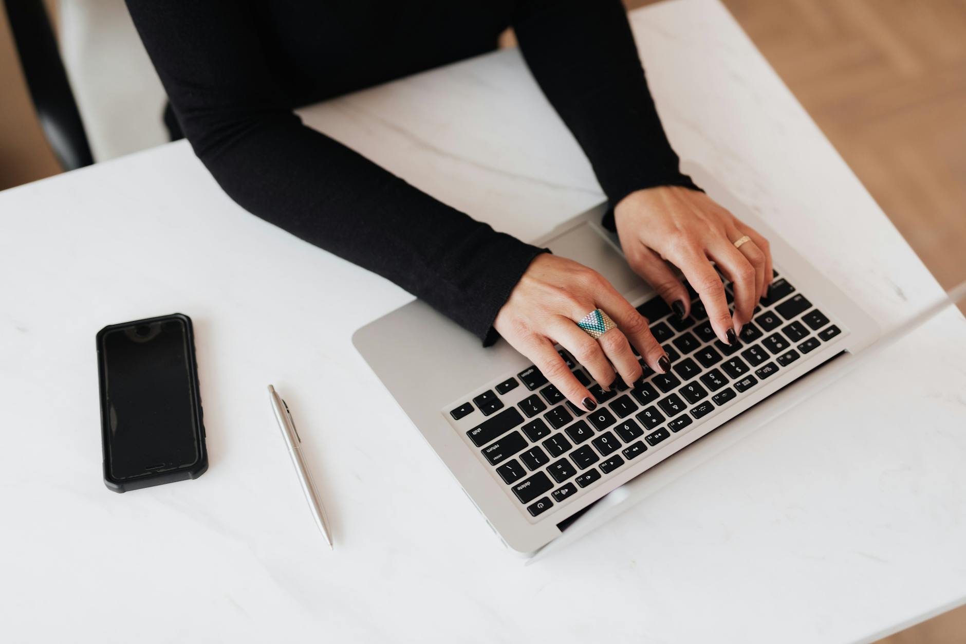 crop faceless woman using laptop at desk in light office